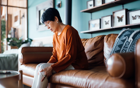 Woman sitting on couch holding her knees.