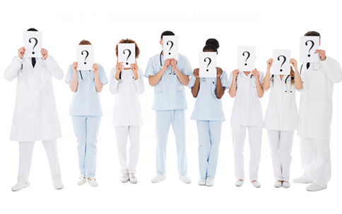 Doctors holding signs with question marks in front of their faces.